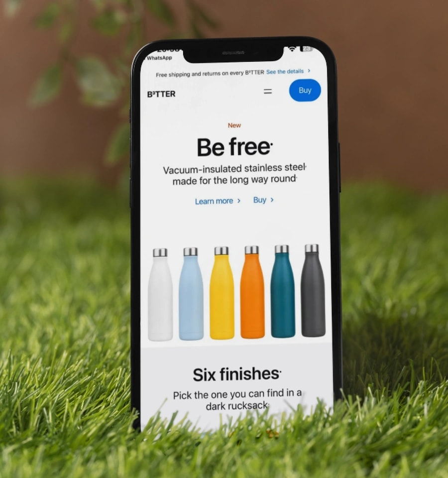 The B3TTER site open on a phone, resting on grass outdoors